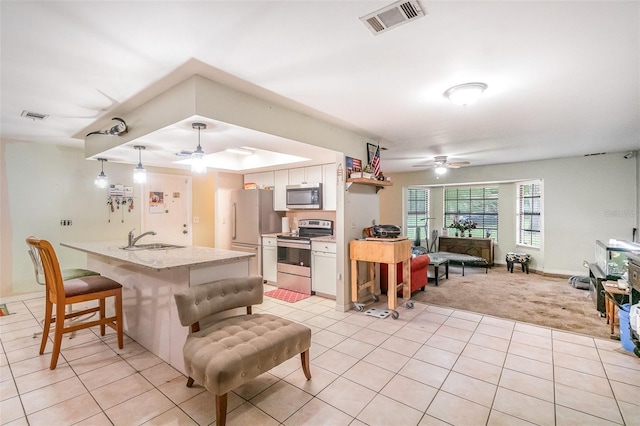 236 Longhorn Dr, Apopka, FL 32712 - kitchen with stainless steel appliances, ceiling fan, white cabinetry, a kitchen bar, and light tile patterned floors