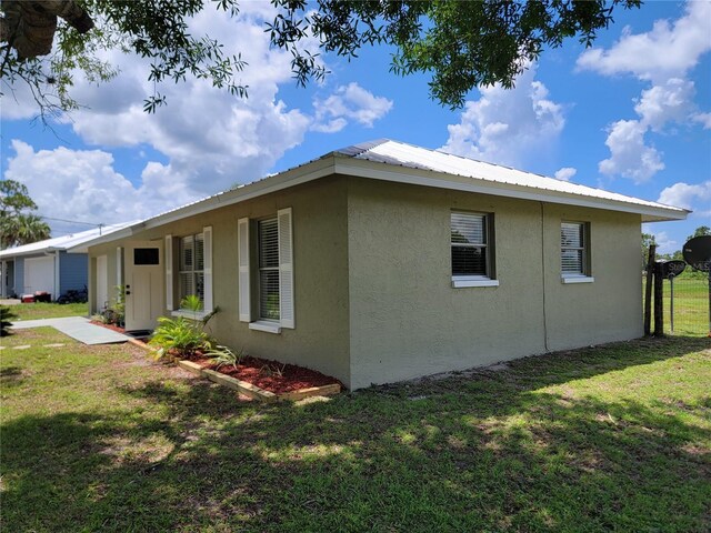 5037 S Obispo Cir, Labelle, FL 33935 - view of side of property featuring stucco siding, a lawn, and a metal roof
