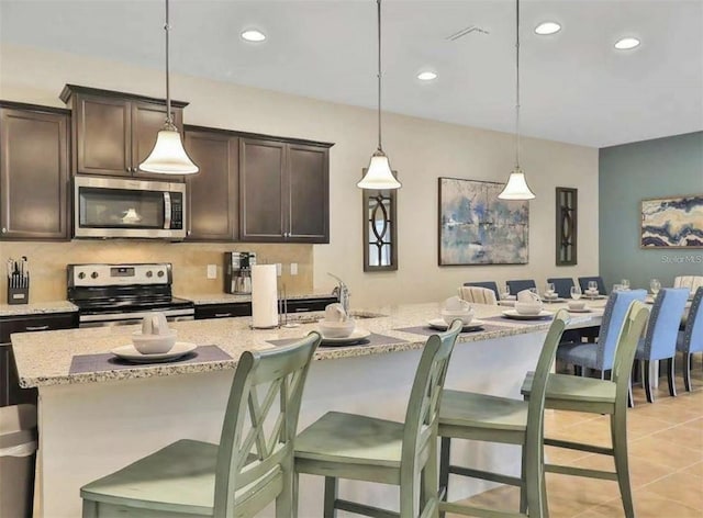 1606 Lima Ave, Kissimmee, FL 34747 - kitchen with stainless steel microwave, electric range, dark brown cabinetry, recessed lighting, and light stone counters