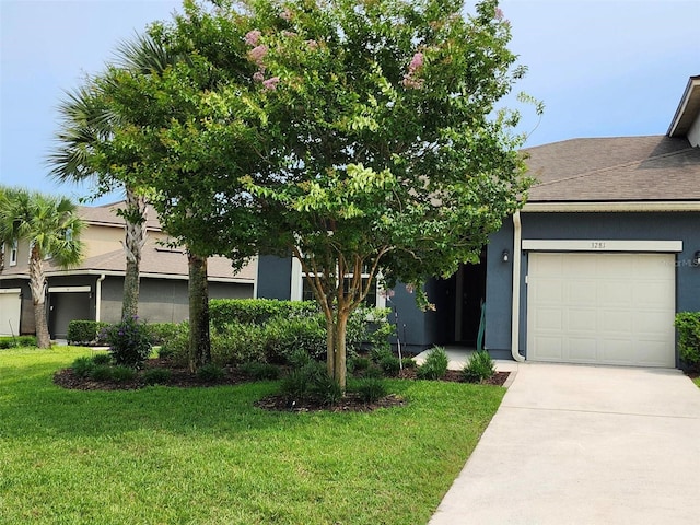 3281 Chestnut Ridge Way, Orange Park, FL 32065 - obstructed view of property with a front lawn, an attached garage, stucco siding, concrete driveway, and roof with shingles
