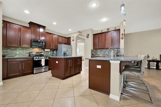 2319 Dammar St, Orlando, FL 32824 - kitchen featuring appliances with stainless steel finishes, arched walkways, tasteful backsplash, light tile patterned flooring, and a peninsula