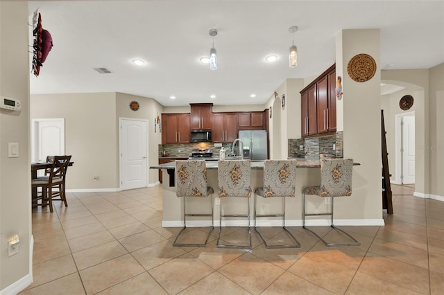 2319 Dammar St, Orlando, FL 32824 - kitchen with appliances with stainless steel finishes, arched walkways, light tile patterned floors, tasteful backsplash, and a peninsula