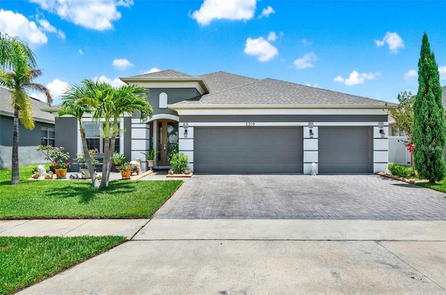 2319 Dammar St, Orlando, FL 32824 - view of front of property featuring decorative driveway, an attached garage, stucco siding, a front yard, and a shingled roof