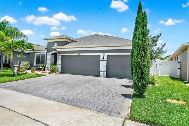 2319 Dammar St, Orlando, FL 32824 - view of front of house with decorative driveway, an attached garage, a gate, stucco siding, and roof with shingles