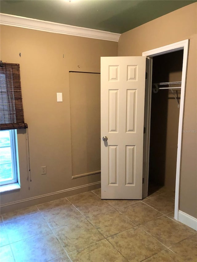 1910 NW 13th Pl, Ocala, FL 34475 - unfurnished bedroom with ornamental molding, a closet, and tile patterned floors