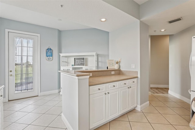4650 Links Village Dr Unit B103, Ponce Inlet, FL 32127 - kitchen with light tile patterned flooring, white cabinets, light countertops, recessed lighting, and a peninsula