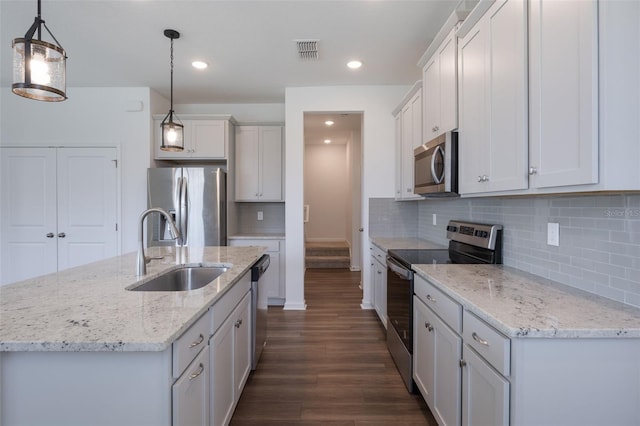 3240 Canna Lily Pl, Clermont, FL 34711 - kitchen with appliances with stainless steel finishes, dark wood-type flooring, backsplash, a kitchen island with sink, and hanging light fixtures