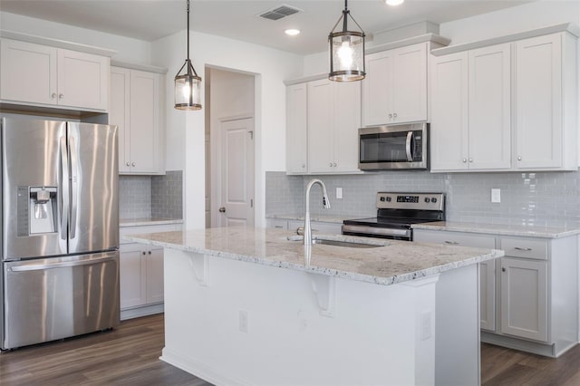 3240 Canna Lily Pl, Clermont, FL 34711 - kitchen with stainless steel appliances, dark wood-style flooring, decorative backsplash, a kitchen island with sink, and recessed lighting