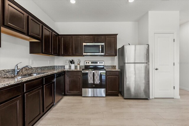 827 Grandin St, Davenport, FL 33837 - kitchen featuring stainless steel appliances, stone counters, dark brown cabinets, light wood finished floors, and recessed lighting