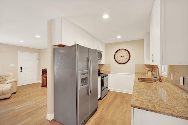 1000 Sal St, Ocoee, FL 34761 - kitchen featuring stainless steel appliances, white cabinetry, light wood finished floors, tasteful backsplash, and recessed lighting