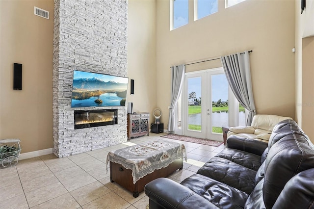 9207 Busaco Park Way, Winter Garden, FL 34787 - living area with a towering ceiling, healthy amount of natural light, a stone fireplace, tile patterned flooring, and french doors