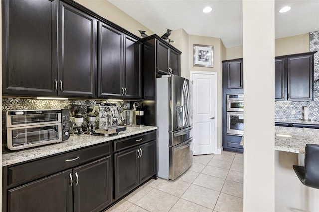 9207 Busaco Park Way, Winter Garden, FL 34787 - kitchen featuring appliances with stainless steel finishes, decorative backsplash, light stone counters, light tile patterned flooring, and recessed lighting