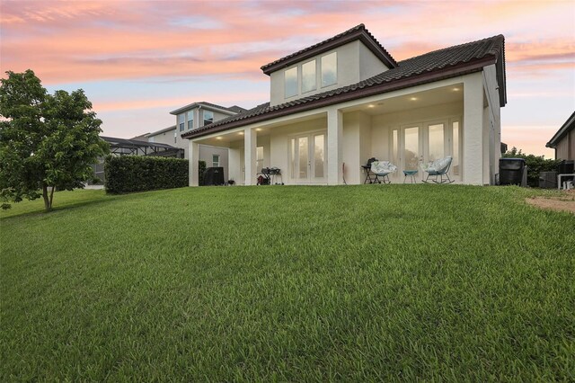 9207 Busaco Park Way, Winter Garden, FL 34787 - back of property at dusk with french doors, a yard, stucco siding, and a tile roof