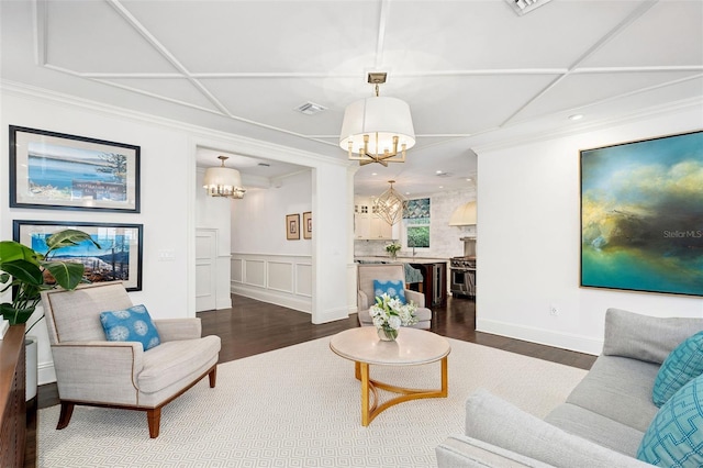 1011 Lake Davis Dr, Orlando, FL 32806 - living room featuring a chandelier, dark wood-type flooring, crown molding, a wainscoted wall, and a decorative wall