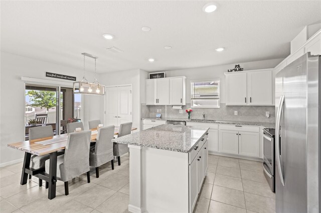 7603 Taormina Way, Clermont, FL 34714 - kitchen with stainless steel appliances, backsplash, a center island, white cabinetry, and recessed lighting