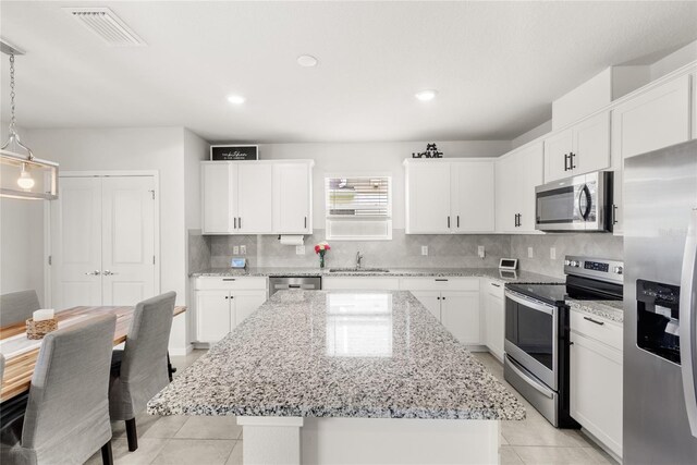 7603 Taormina Way, Clermont, FL 34714 - kitchen featuring appliances with stainless steel finishes, light tile patterned flooring, a center island, decorative backsplash, and recessed lighting