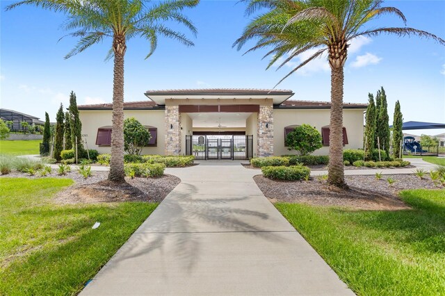 7603 Taormina Way, Clermont, FL 34714 - view of front of house with a gate, stucco siding, stone siding, and a tile roof