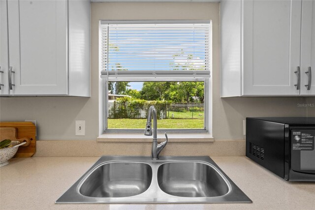 110 Rabun Ct, Sanford, FL 32773 - kitchen with black microwave, white cabinets, and light countertops