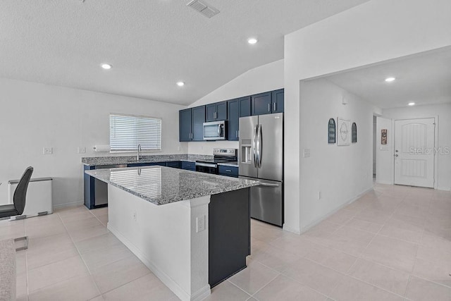 232 Summerlin Loop, Haines City, FL 33844 - kitchen featuring appliances with stainless steel finishes, light stone counters, a kitchen island, vaulted ceiling, and light tile patterned floors