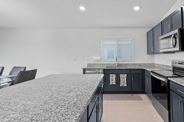 232 Summerlin Loop, Haines City, FL 33844 - kitchen with appliances with stainless steel finishes, a textured ceiling, light tile patterned flooring, recessed lighting, and light stone counters