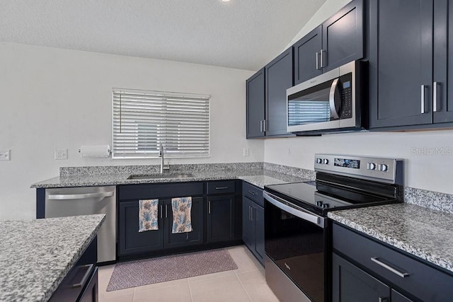232 Summerlin Loop, Haines City, FL 33844 - kitchen with appliances with stainless steel finishes, a textured ceiling, light tile patterned floors, and light stone countertops
