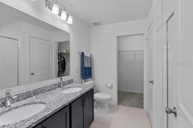 232 Summerlin Loop, Haines City, FL 33844 - bathroom featuring a spacious closet, a shower stall, double vanity, a textured ceiling, and tile patterned flooring