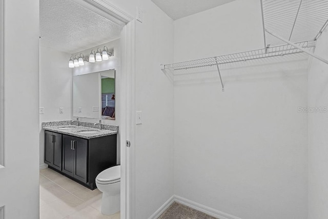 232 Summerlin Loop, Haines City, FL 33844 - bathroom with double vanity, a spacious closet, tile patterned floors, and a textured ceiling