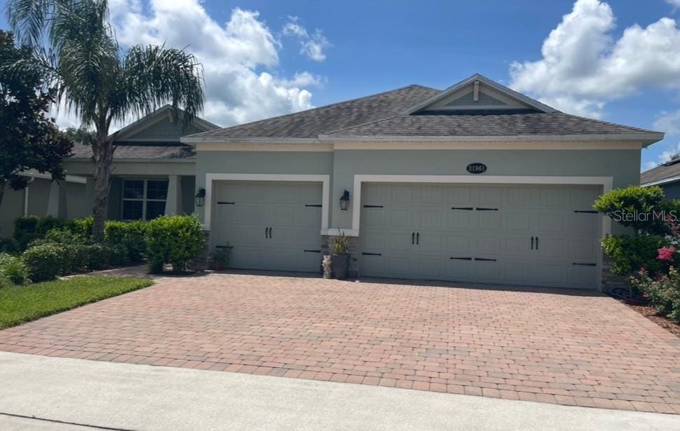 31961 Redtail Reserve Blvd, Sorrento, FL 32776 - view of front of house with an attached garage, decorative driveway, roof with shingles, and stucco siding