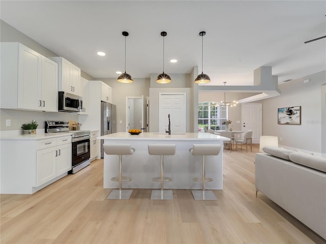 2823 NE 24th Pl, Ocala, FL 34470 - kitchen featuring appliances with stainless steel finishes, light wood finished floors, open floor plan, a breakfast bar area, and recessed lighting