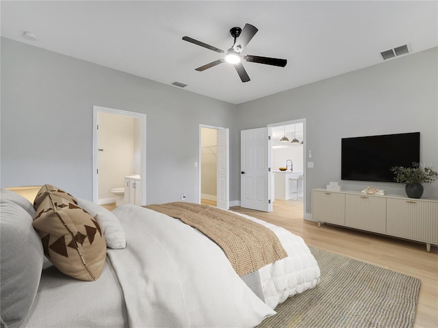 2823 NE 24th Pl, Ocala, FL 34470 - bedroom featuring light wood-type flooring, a spacious closet, ensuite bathroom, and a ceiling fan