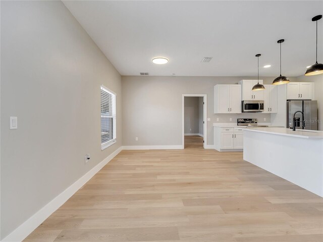 2823 NE 24th Pl, Ocala, FL 34470 - kitchen featuring appliances with stainless steel finishes, light countertops, white cabinets, light wood-type flooring, and recessed lighting
