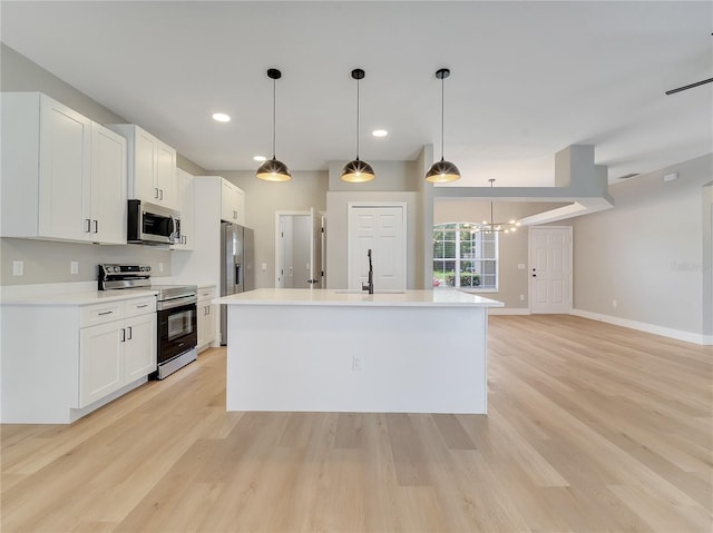 2823 NE 24th Pl, Ocala, FL 34470 - kitchen with stainless steel appliances, light wood finished floors, a kitchen island with sink, white cabinetry, and recessed lighting