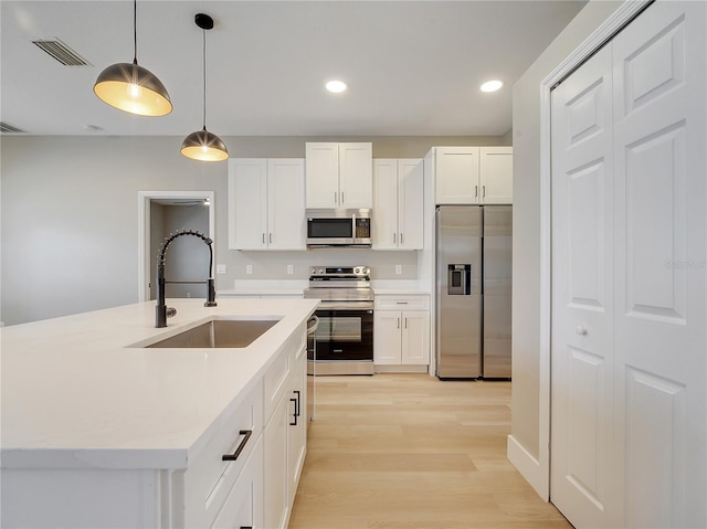 2823 NE 24th Pl, Ocala, FL 34470 - kitchen featuring appliances with stainless steel finishes, light wood-style floors, hanging light fixtures, light countertops, and white cabinetry