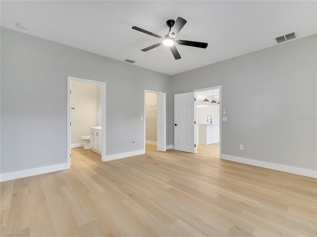 2823 NE 24th Pl, Ocala, FL 34470 - unfurnished bedroom featuring a walk in closet, light wood-style flooring, ensuite bath, a closet, and ceiling fan