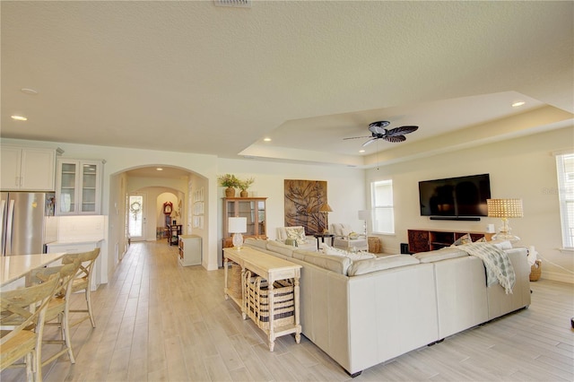 1774 Pasture Loop, Oviedo, FL 32765 - living area featuring arched walkways, a ceiling fan, recessed lighting, light wood-style floors, and a tray ceiling