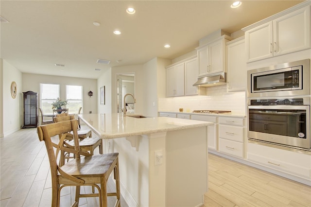 1774 Pasture Loop, Oviedo, FL 32765 - kitchen featuring stainless steel appliances, under cabinet range hood, light wood-style floors, tasteful backsplash, and recessed lighting