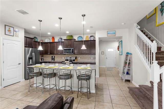 1909 Majorca Dr, Kissimmee, FL 34747 - kitchen with appliances with stainless steel finishes, dark brown cabinetry, light tile patterned floors, a kitchen breakfast bar, and recessed lighting