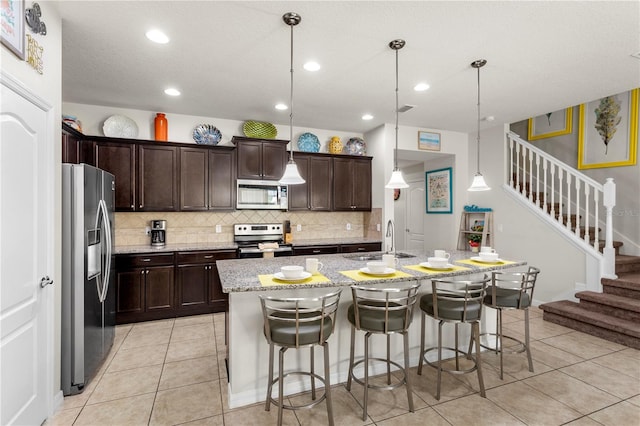 1909 Majorca Dr, Kissimmee, FL 34747 - kitchen featuring appliances with stainless steel finishes, tasteful backsplash, a kitchen breakfast bar, dark brown cabinets, and light stone counters