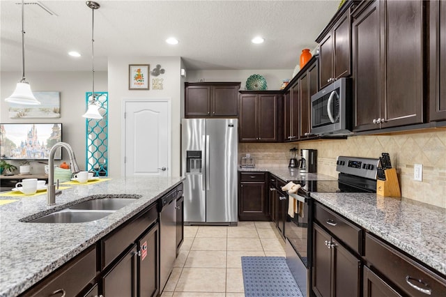 1909 Majorca Dr, Kissimmee, FL 34747 - kitchen featuring appliances with stainless steel finishes, decorative backsplash, light stone countertops, dark brown cabinetry, and recessed lighting