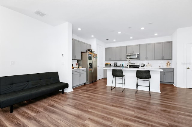 812 Benoi Dr, Davenport, FL 33896 - kitchen with gray cabinets, appliances with stainless steel finishes, recessed lighting, wood finished floors, and a kitchen island with sink
