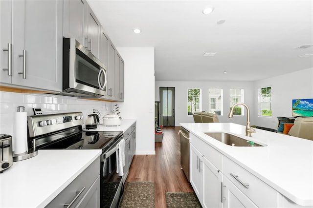 812 Benoi Dr, Davenport, FL 33896 - kitchen with stainless steel appliances, open floor plan, dark wood-style flooring, light countertops, and tasteful backsplash