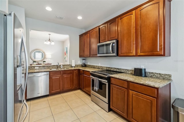 2616 Bowring St, Kissimmee, FL 34747 - kitchen featuring appliances with stainless steel finishes, light stone counters, light tile patterned floors, a chandelier, and brown cabinets