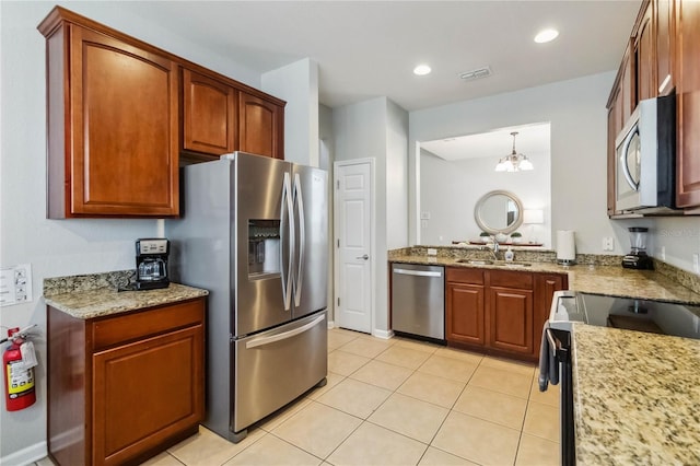 2616 Bowring St, Kissimmee, FL 34747 - kitchen with stainless steel appliances, light tile patterned floors, light stone countertops, a chandelier, and brown cabinets