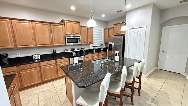 8940 Sugar Palm Rd, Kissimmee, FL 34747 - kitchen with stainless steel appliances, light tile patterned floors, hanging light fixtures, a center island with sink, and a kitchen bar