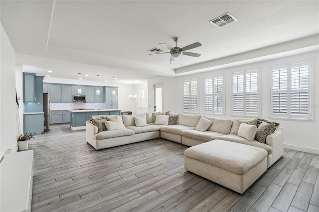 530 Harriswood Ct, Davenport, FL 33837 - living room featuring light wood-style flooring, a tray ceiling, a ceiling fan, recessed lighting, and a chandelier