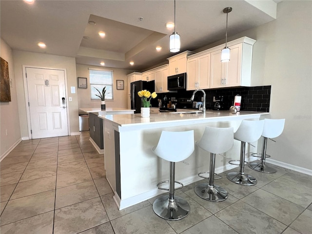 4751 Clock Tower Dr Unit 304, Kissimmee, FL 34746 - kitchen with freestanding refrigerator, a peninsula, a breakfast bar area, light countertops, and tasteful backsplash