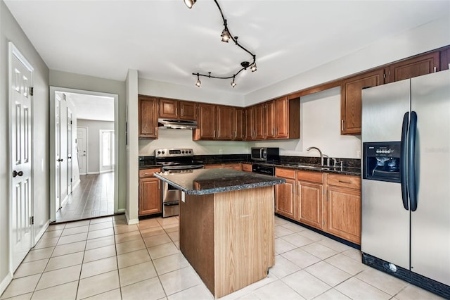 609 S Glen Ave Unit E, Tampa, FL 33609 - kitchen featuring appliances with stainless steel finishes, under cabinet range hood, a center island, light tile patterned floors, and dark stone countertops