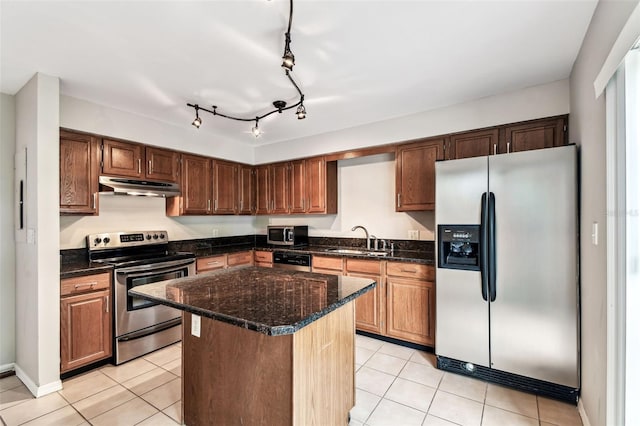 609 S Glen Ave Unit E, Tampa, FL 33609 - kitchen featuring appliances with stainless steel finishes, under cabinet range hood, a center island, light tile patterned flooring, and dark stone countertops