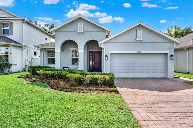 1061 Castlevecchio Loop, Orlando, FL 32825 - view of front facade featuring decorative driveway, stucco siding, an attached garage, and a front yard