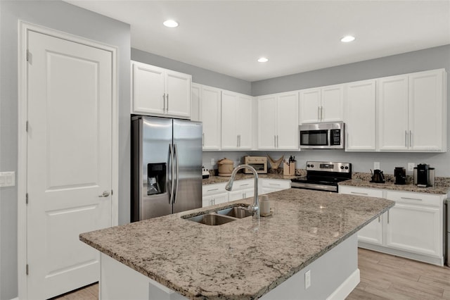 1061 Castlevecchio Loop, Orlando, FL 32825 - kitchen featuring appliances with stainless steel finishes, white cabinetry, light stone countertops, a kitchen island with sink, and recessed lighting